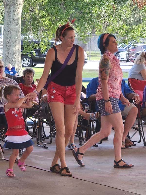 Two women and a little girl are dancing in front of a crowd