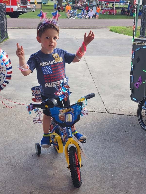A young boy wearing a shirt that says redskins is riding a bike