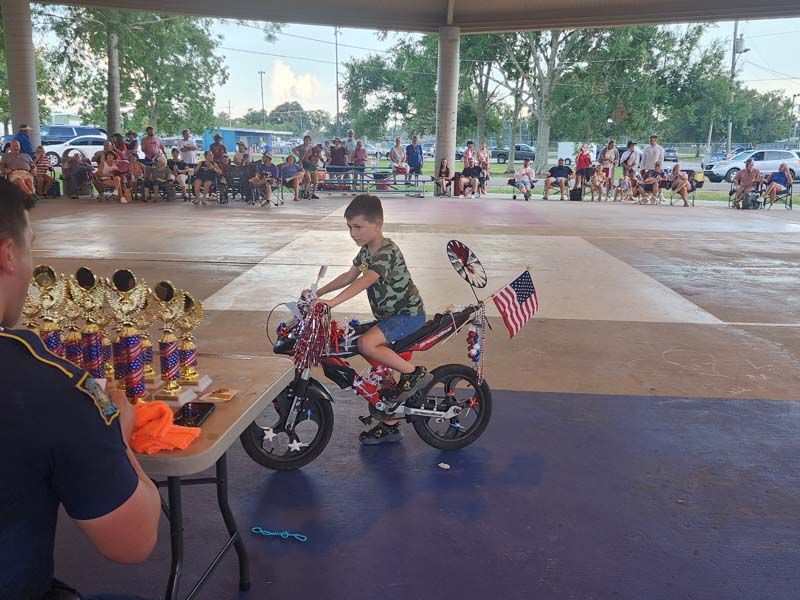 A young boy is riding a bike decorated with american flags.