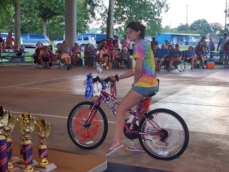 A girl is riding a bike in front of trophies