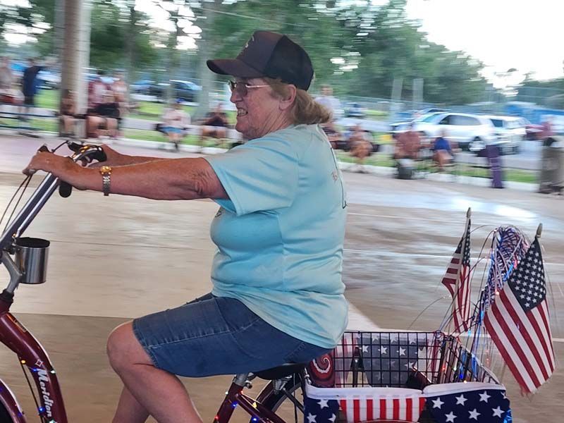 A woman is riding a bike with american flags on the back