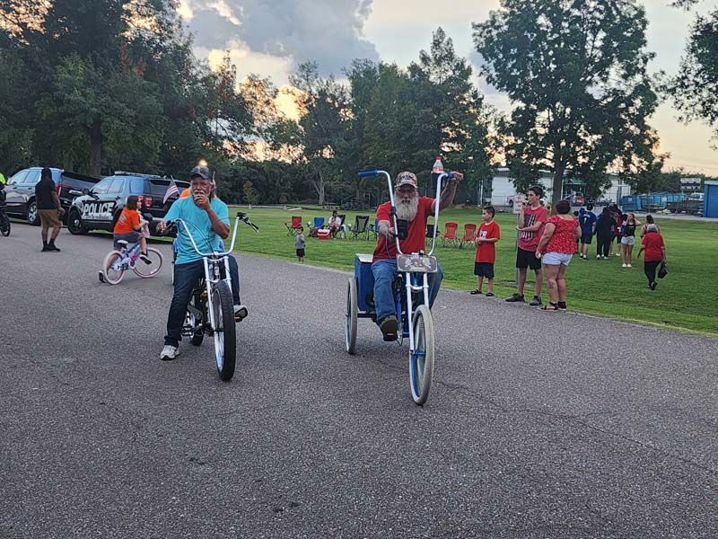 A group of people are riding motorcycles and tricycles in a park.