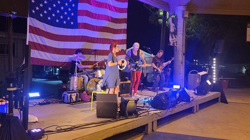 A group of people are standing on a stage in front of an american flag.