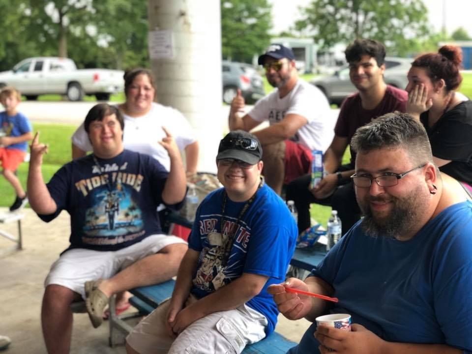 A group of people are sitting at a picnic table eating ice cream.
