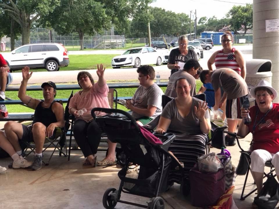 A group of people are sitting at a picnic table in a park.