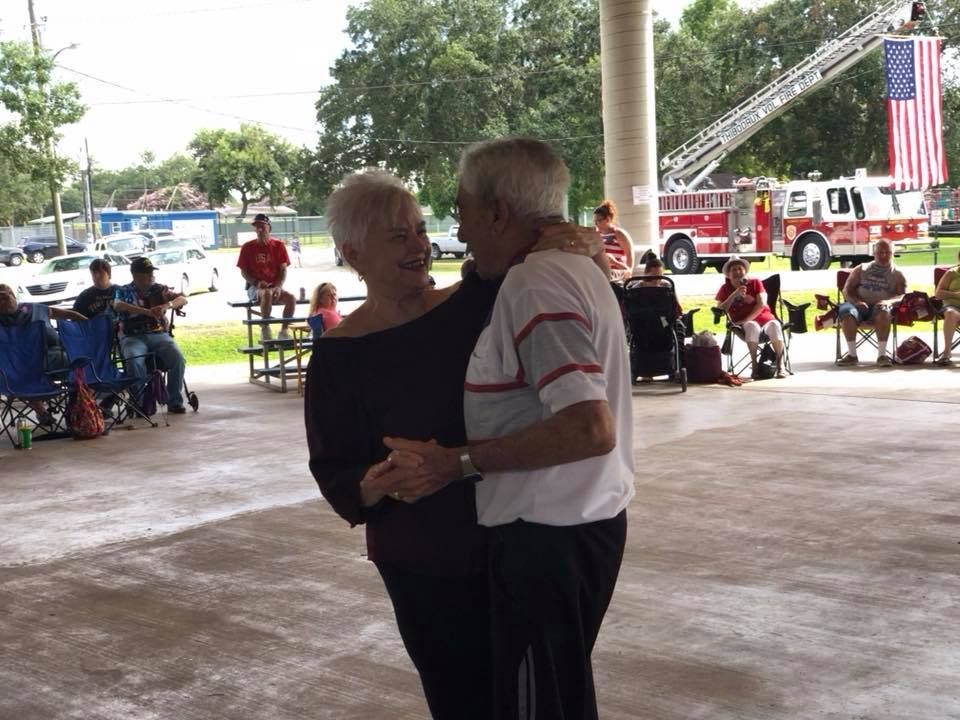 A man and woman are dancing under a pavilion with a fire truck in the background