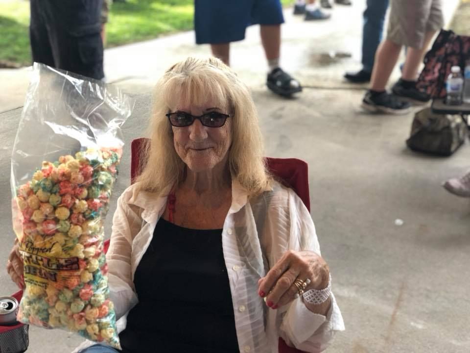 A woman is sitting in a chair holding a bag of popcorn.