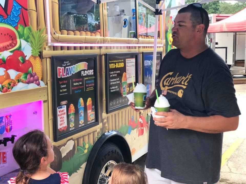 A man and two children are standing in front of a food truck.