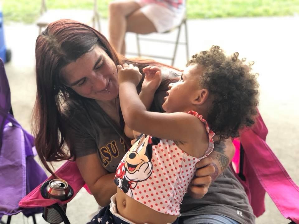 A woman is holding a little girl who is wearing a minnie mouse shirt