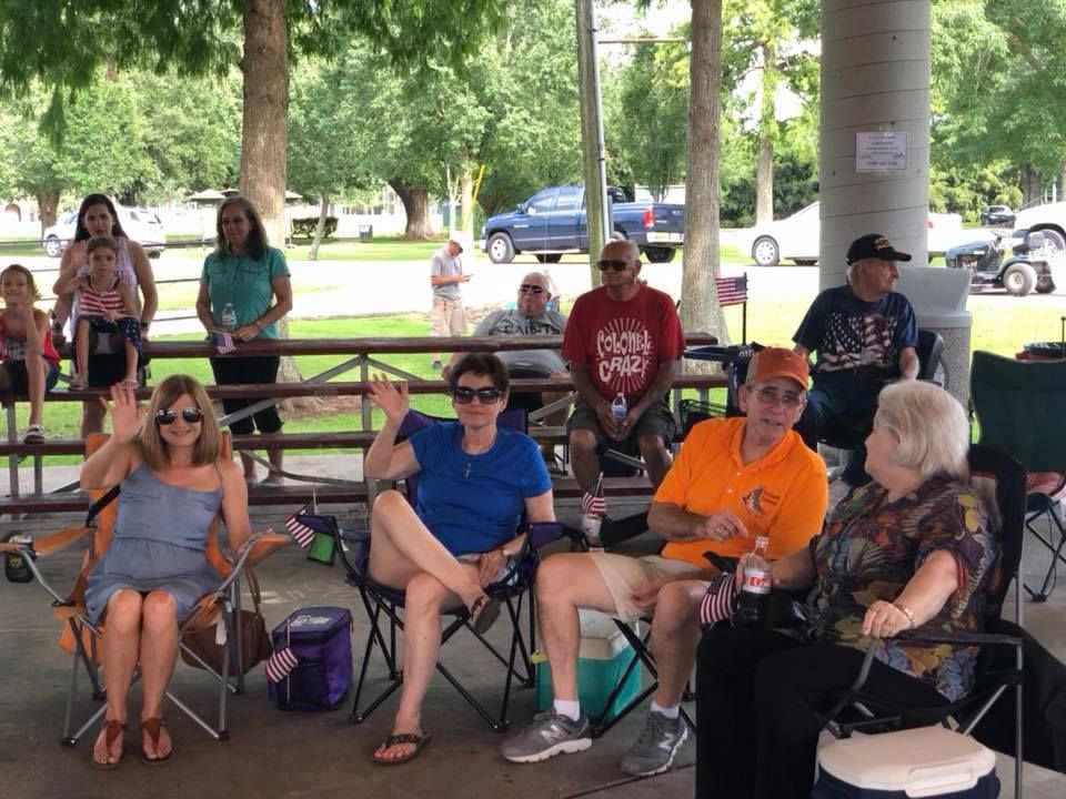 A group of people are sitting in folding chairs under a pavilion.