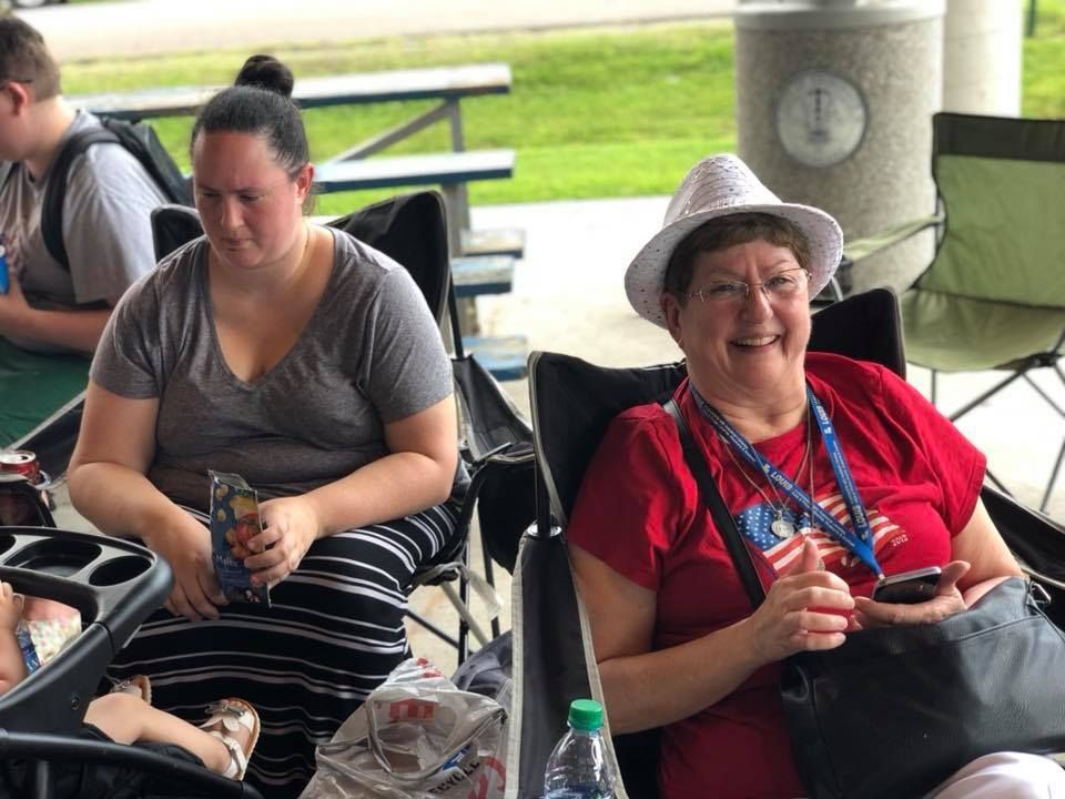 Two women are sitting in chairs at a picnic table.