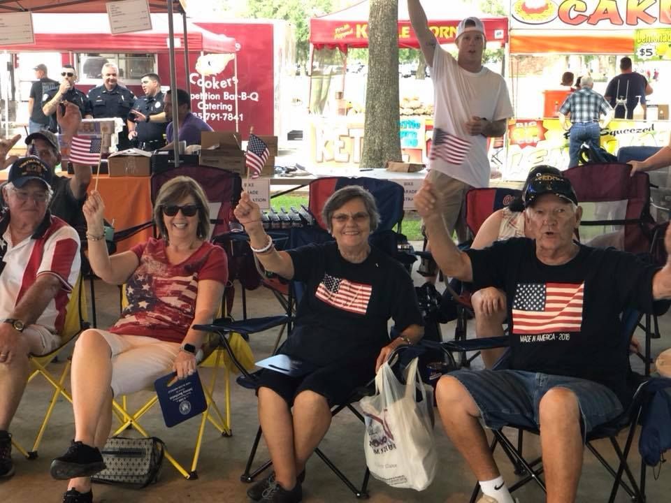 A group of people are sitting in chairs holding american flags.