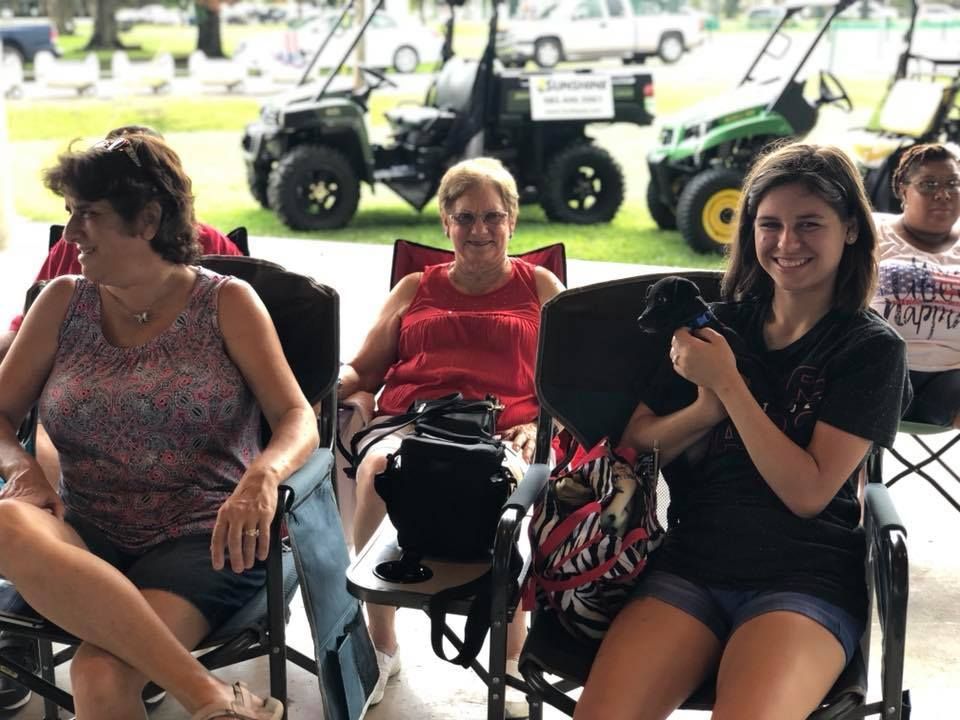 A group of women are sitting in chairs in front of a golf cart.