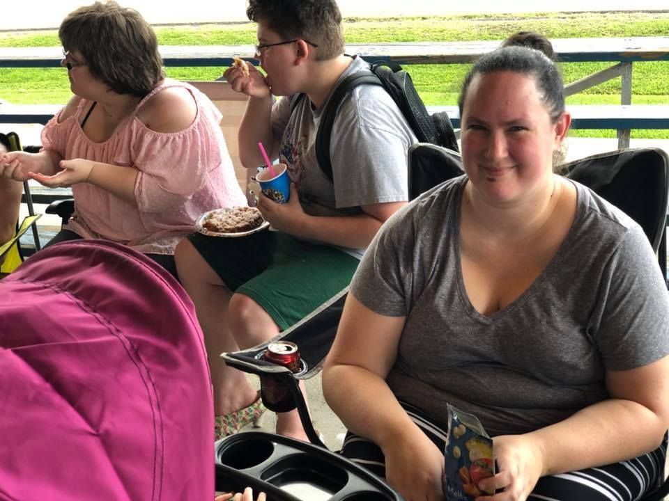 A group of people are sitting at a picnic table eating food.