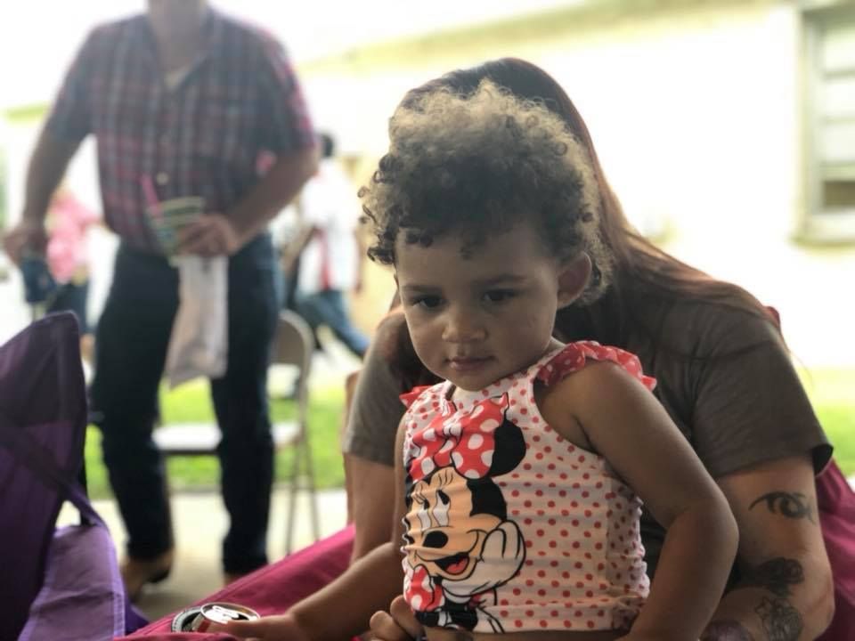 A little girl wearing a minnie mouse shirt is sitting on a woman 's lap