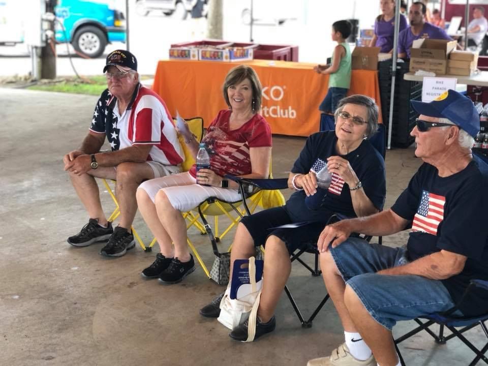 A group of people are sitting in folding chairs under a tent.