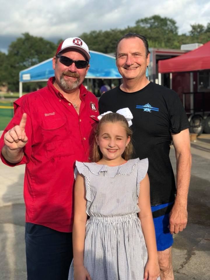 Two men and a little girl are posing for a picture.