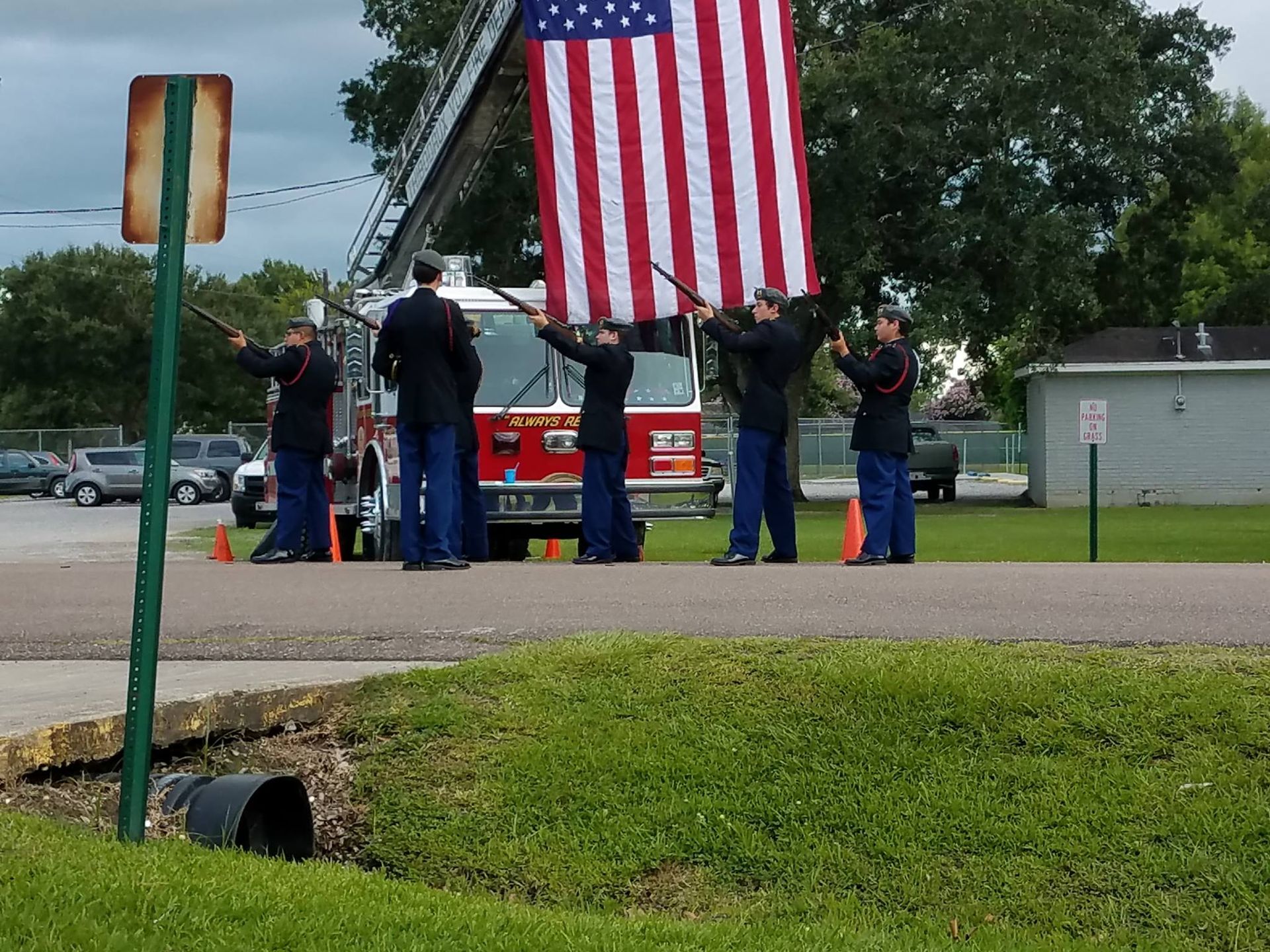 A group of men holding an american flag in front of a fire truck