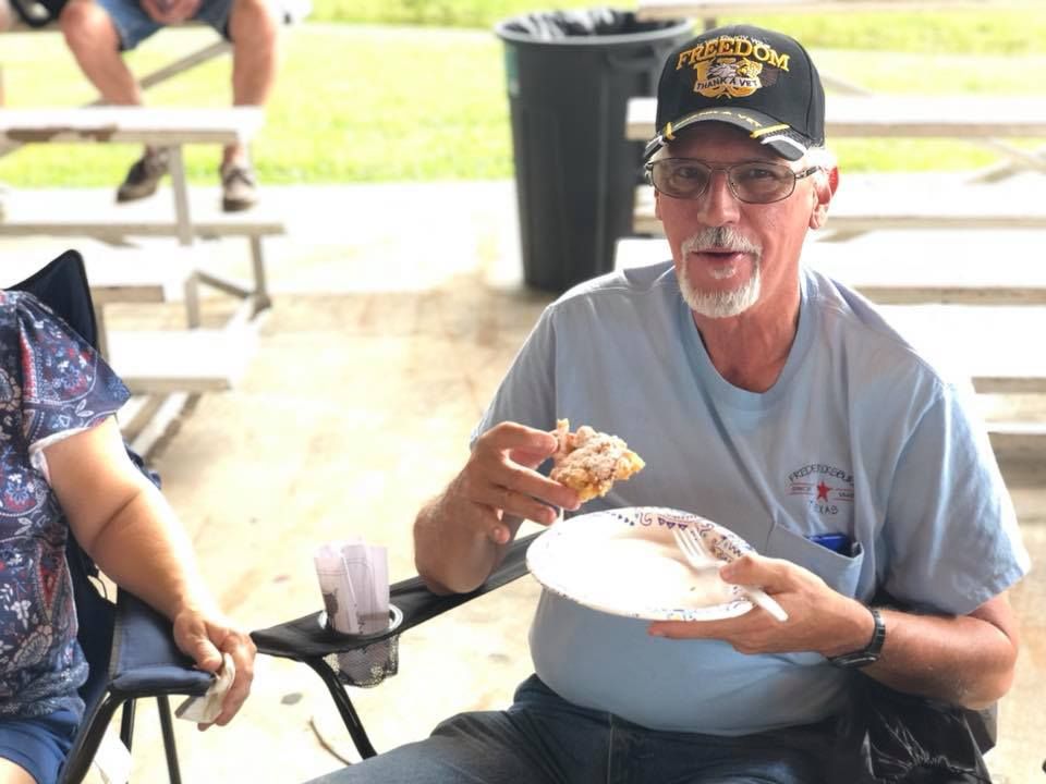 A man is sitting in a chair eating a piece of pizza.
