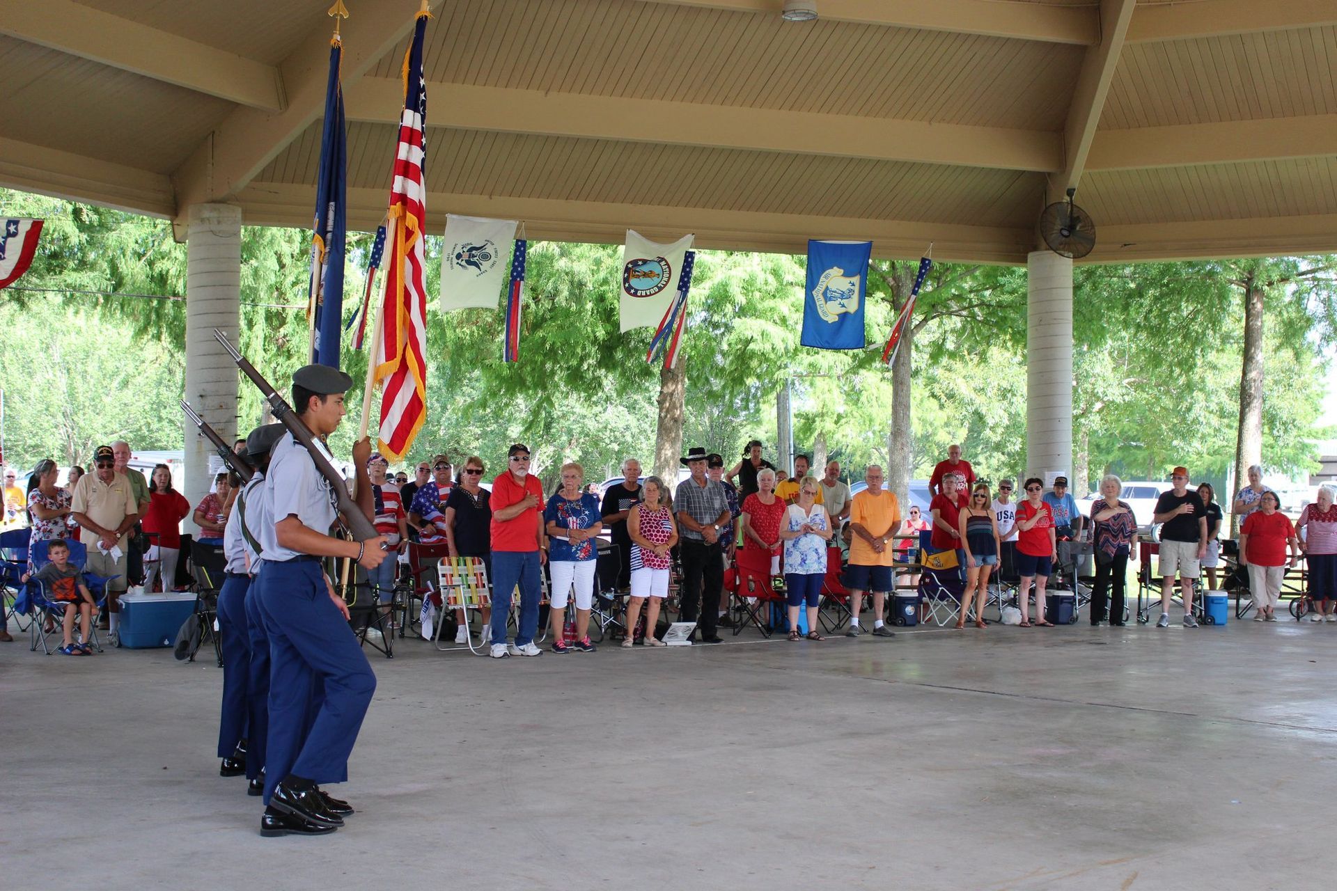 A group of people standing under a pavilion with flags hanging from the ceiling