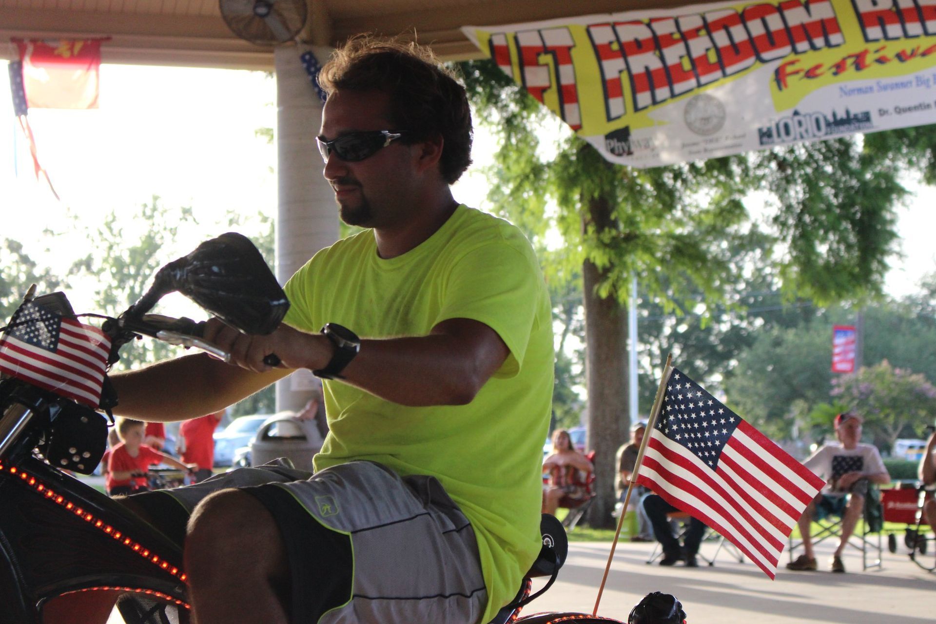 A man in a neon yellow shirt is riding a motorcycle
