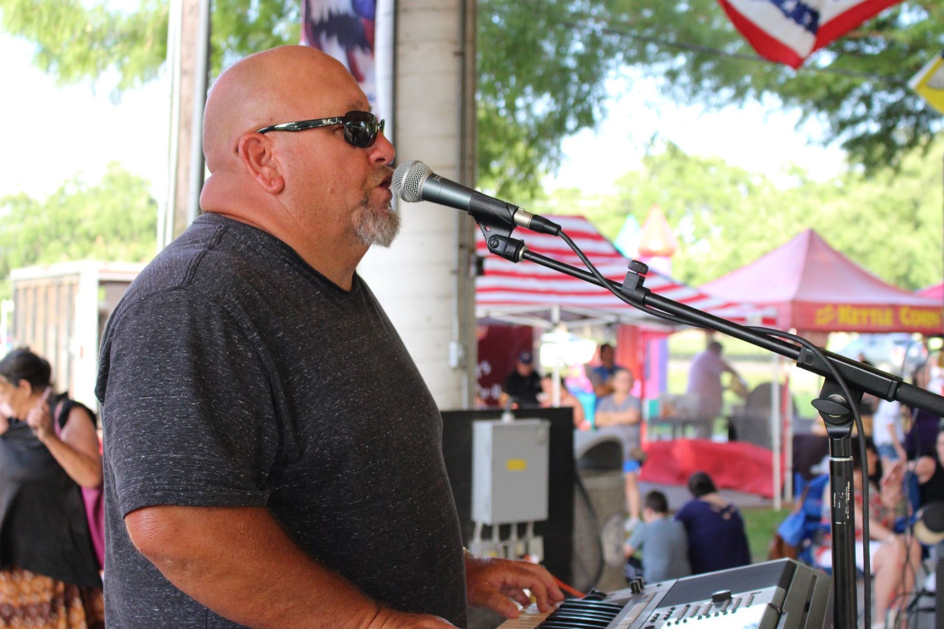 A man is singing into a microphone while playing a keyboard.