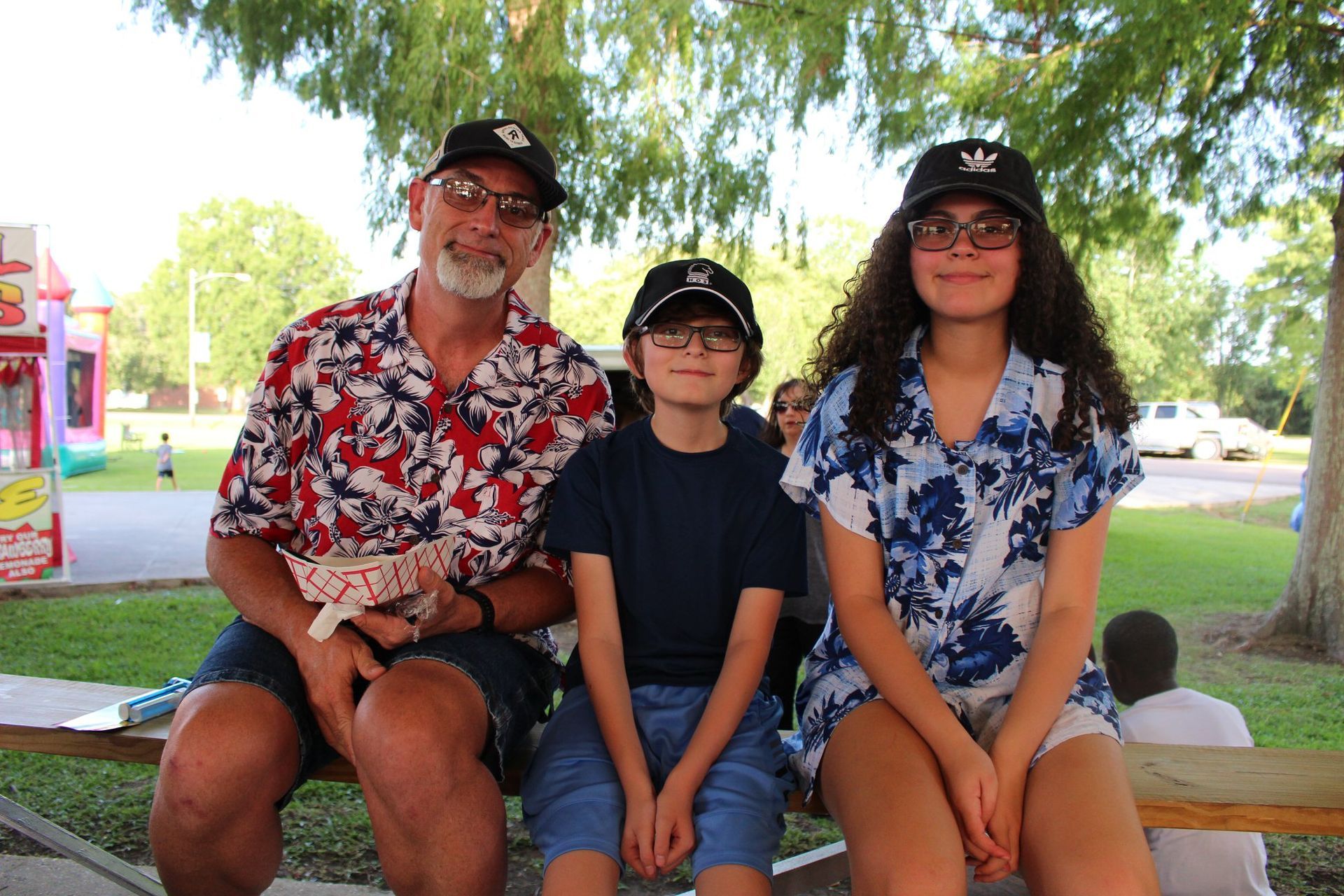 A man and two children are sitting on a bench in a park.
