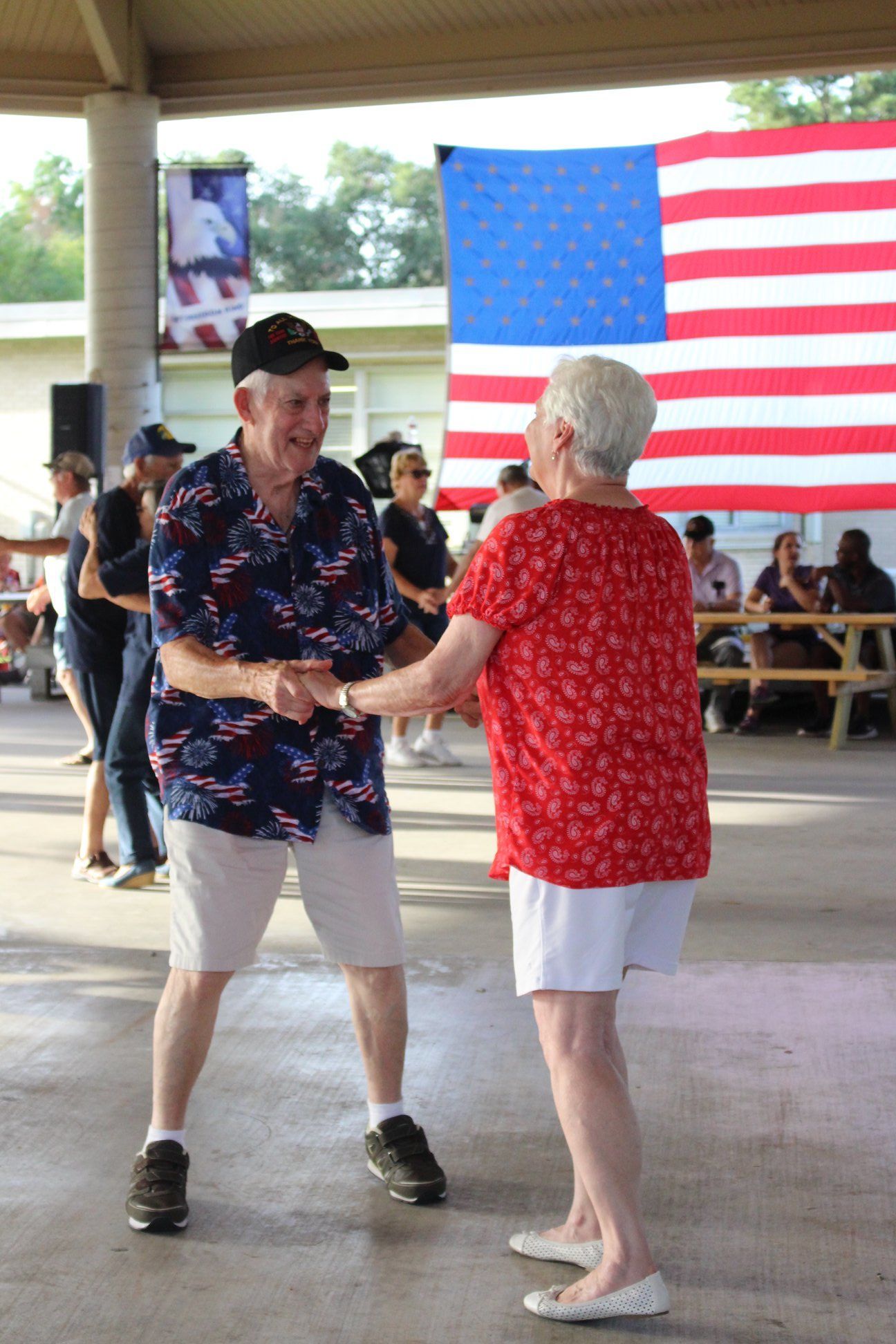 A man and a woman are dancing in front of an american flag.