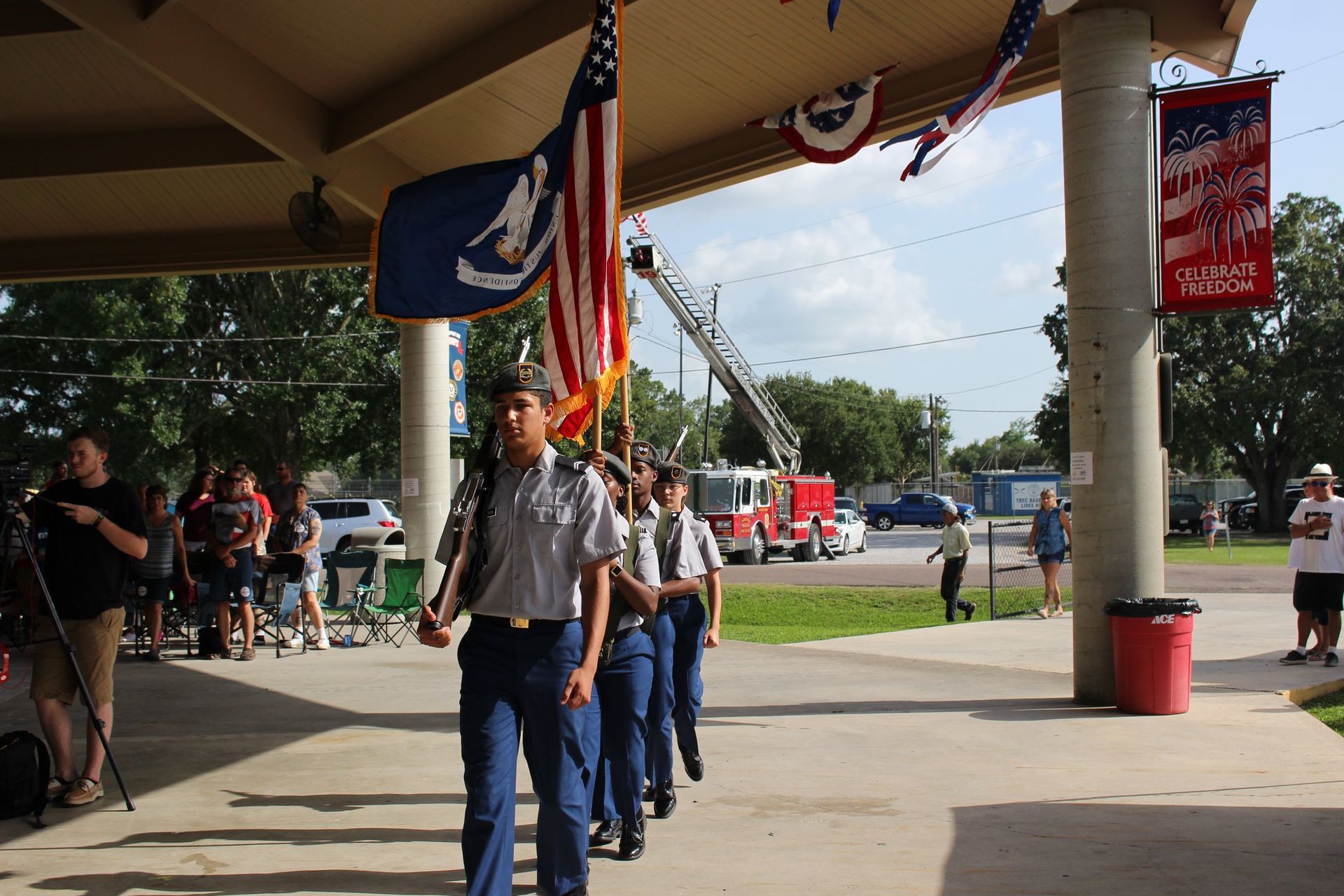 A group of people marching in a parade with a fire truck in the background