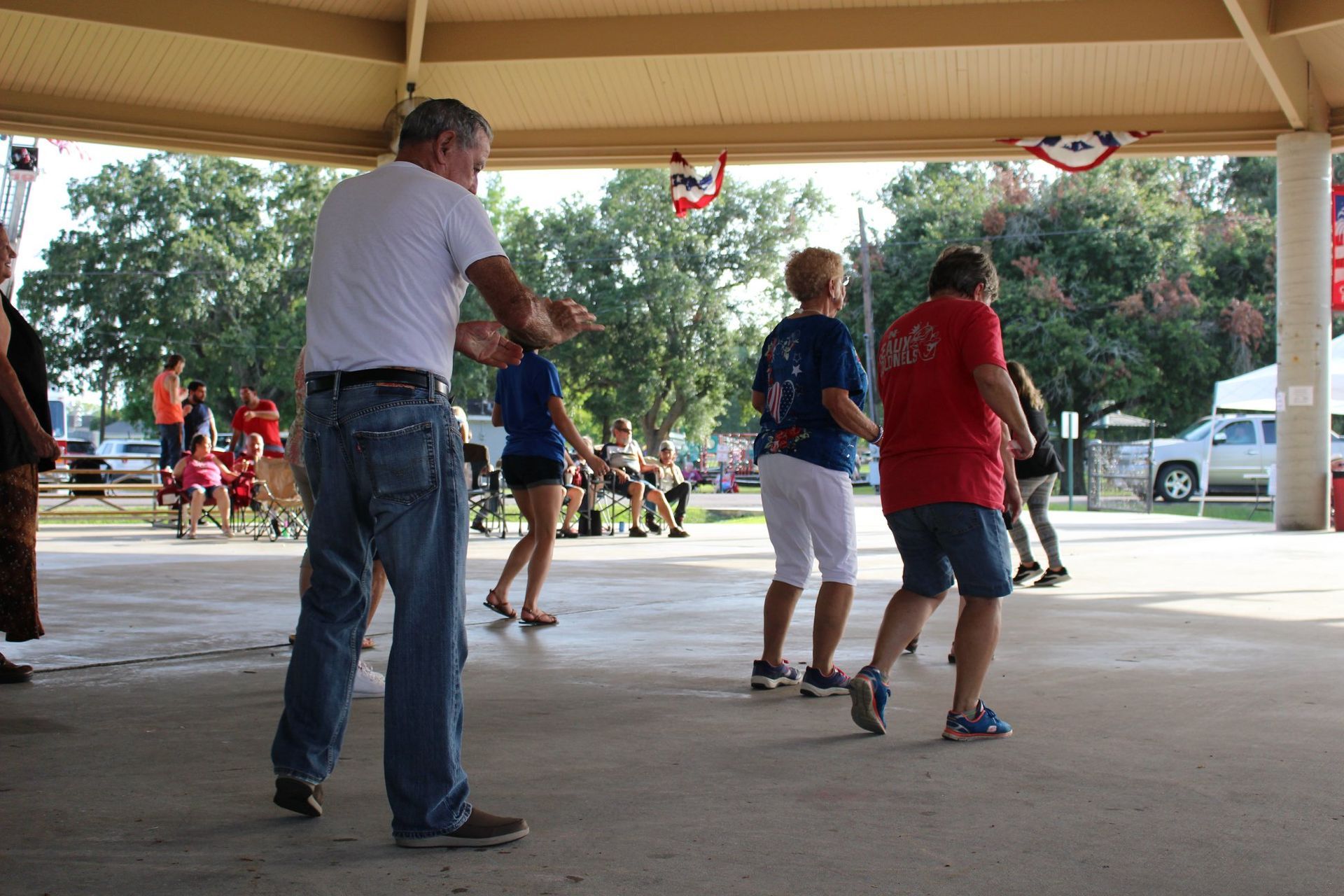 A group of people are dancing under a canopy in a park