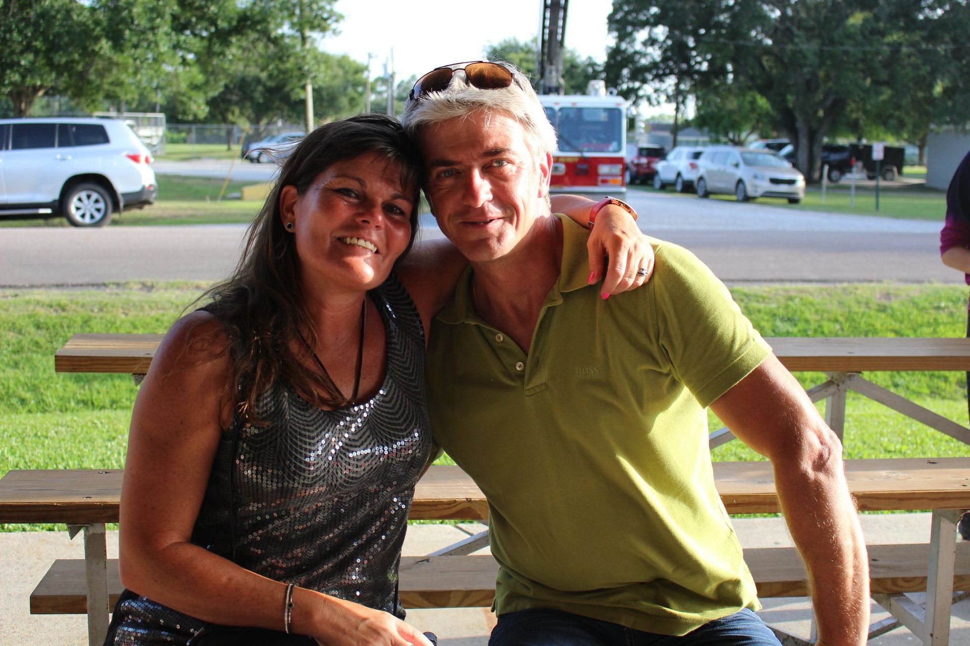 A man and a woman are posing for a picture at a picnic table