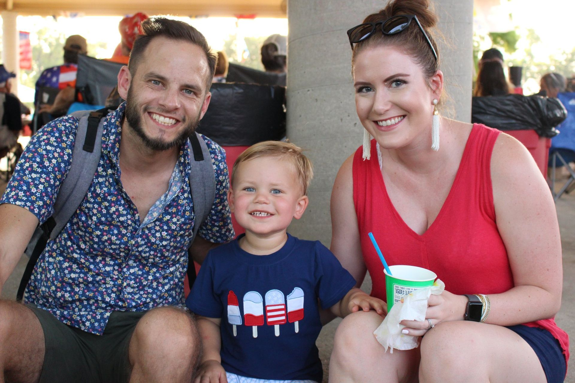 A man , woman and child are sitting next to each other and smiling.