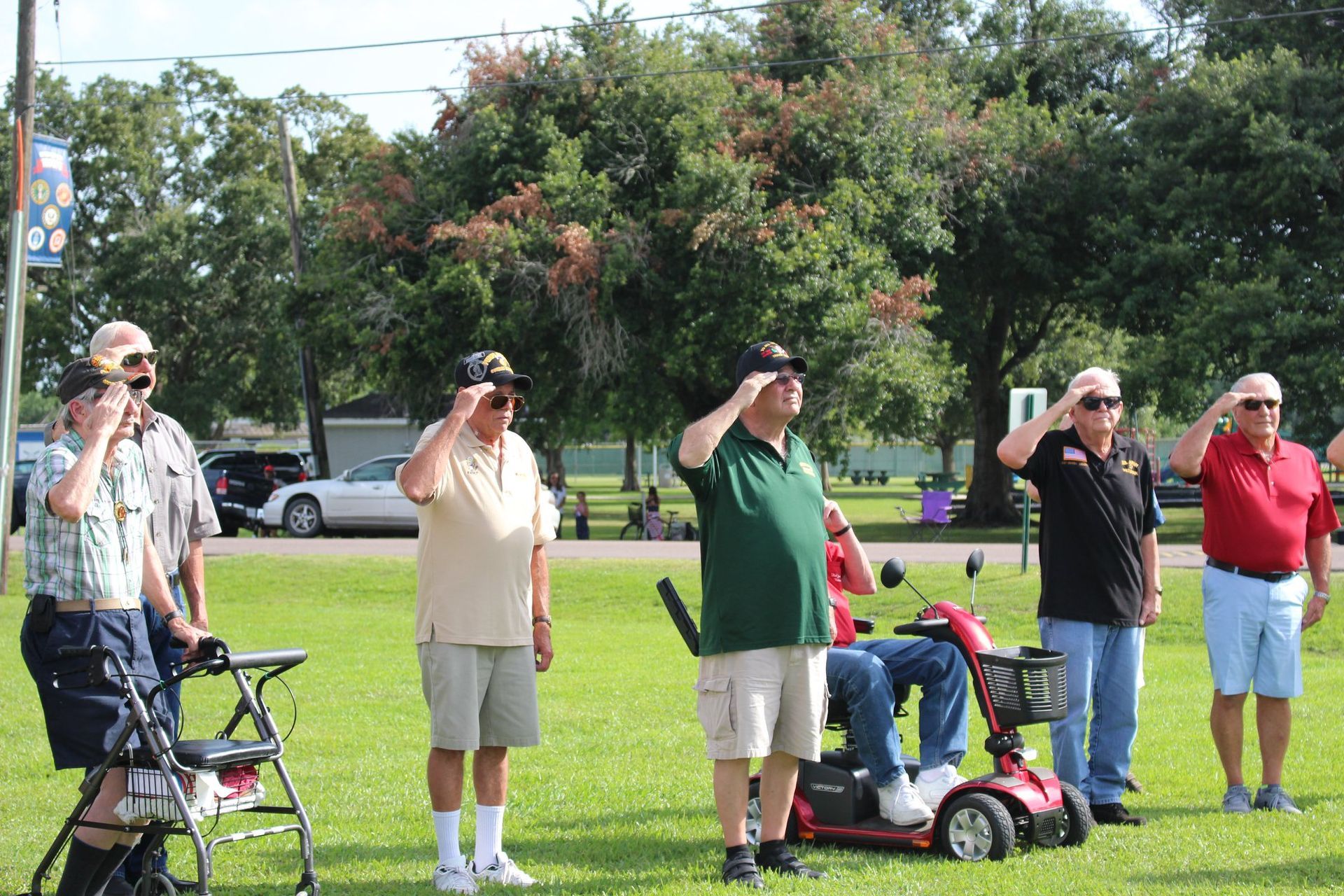 A group of men are saluting in a park.
