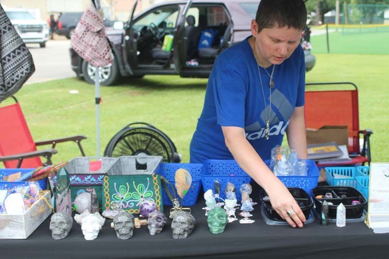 A boy in a blue shirt is standing behind a table with skulls on it.