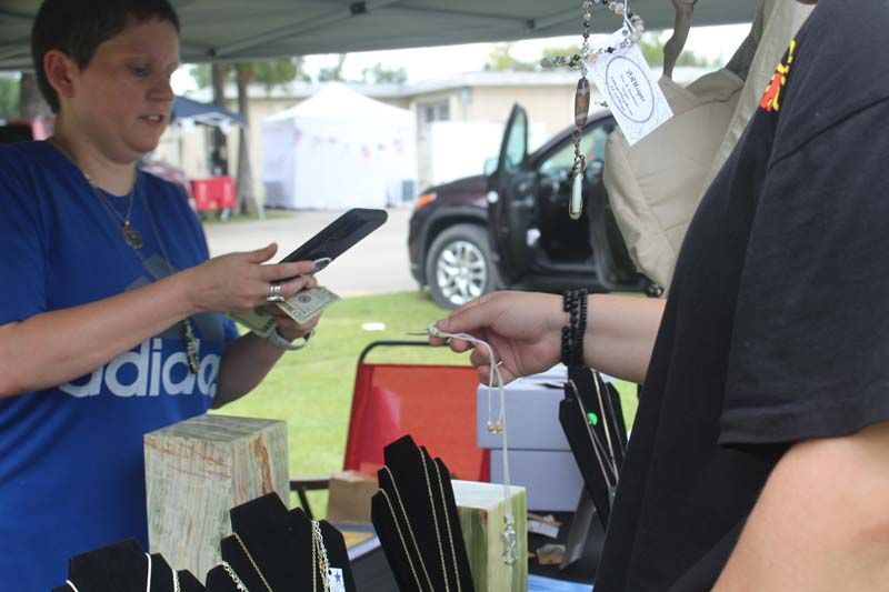 A woman wearing a blue adidas shirt is selling jewelry