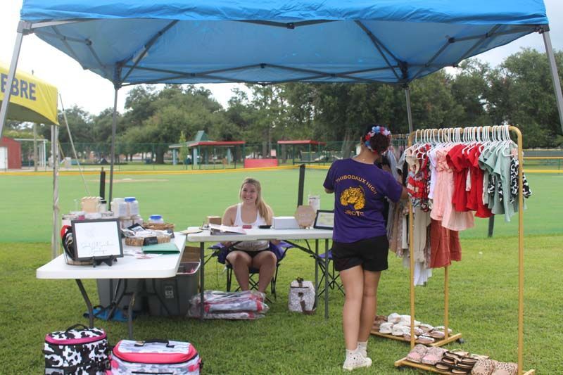 A woman is standing in front of a table under a blue tent.