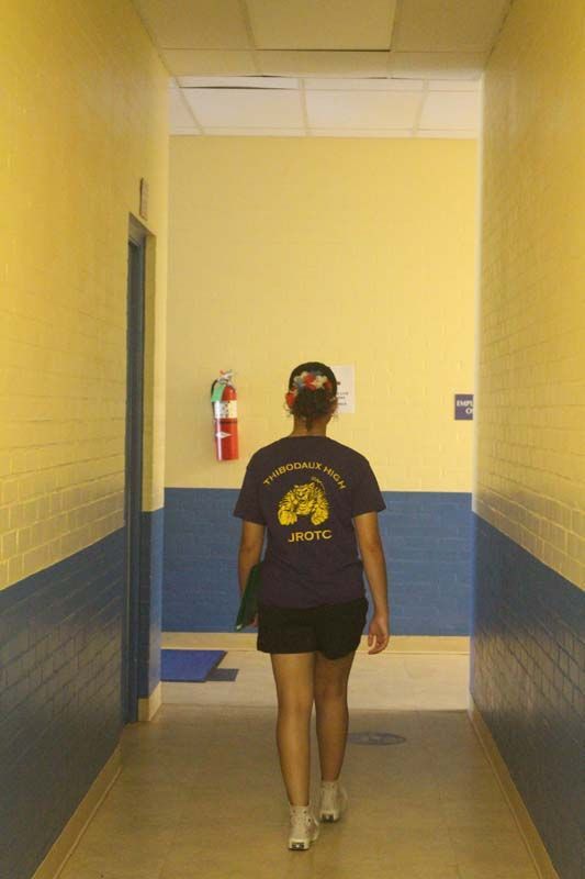 A woman walking down a hallway wearing a shirt that says nyc