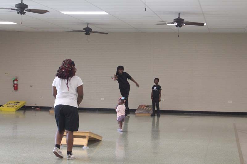 A woman and two children are playing a game in a gym