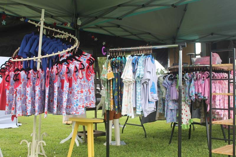 A bunch of clothes are hanging on racks outside of a tent.