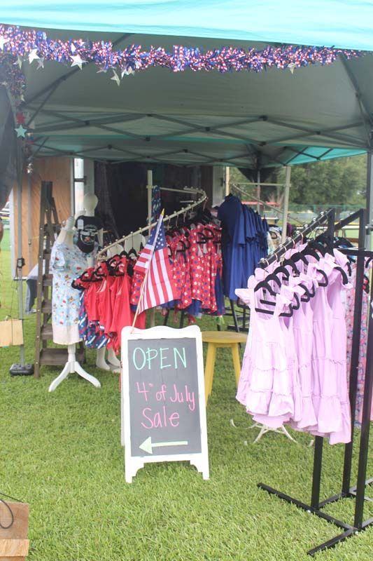 A tent filled with clothes and a sign that says `` open 4th of july sale ''.