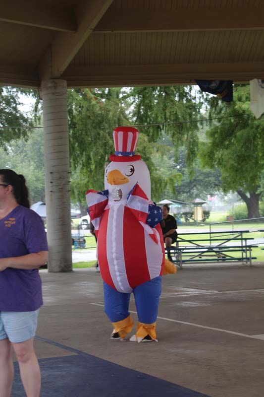 A woman in a purple shirt is standing next to an inflatable chicken