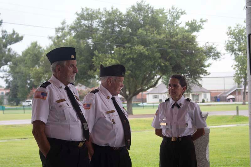 Three men and a woman in military uniforms are standing in a park