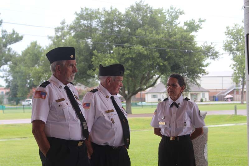 Three men and a woman in uniform are standing in a park