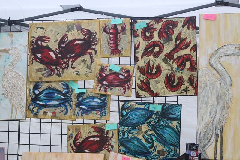 A bunch of paintings of crabs and fish are hanging on a wall