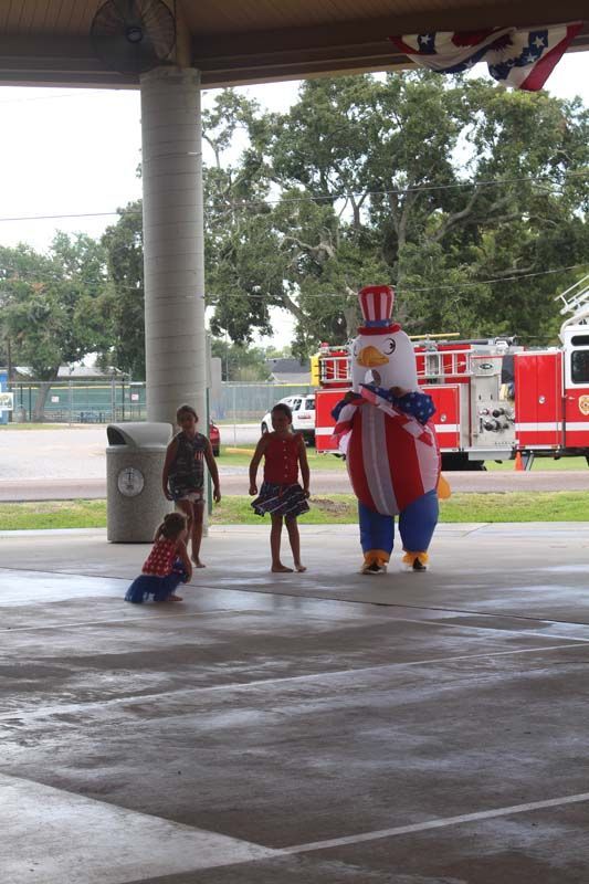 A group of children standing around a mascot dressed as uncle sam