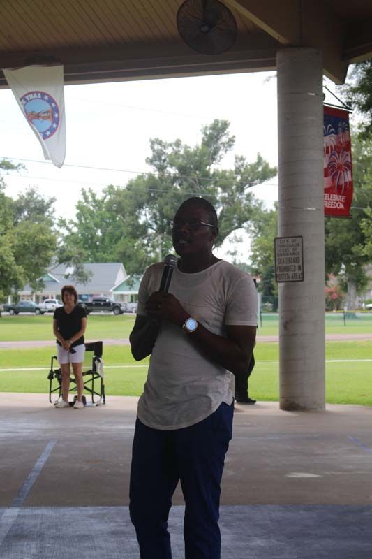 A man is standing under a canopy holding a microphone.