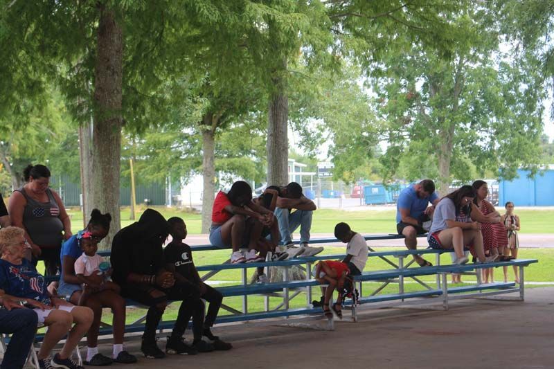 A group of people are sitting on bleachers in a park.