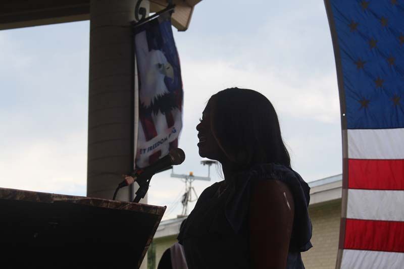 A woman stands in front of an american flag