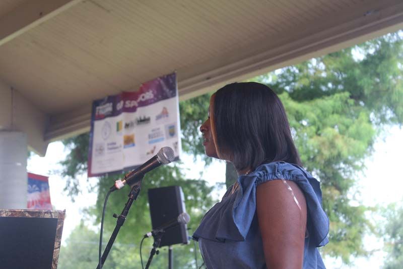 A woman is singing into a microphone under a canopy.