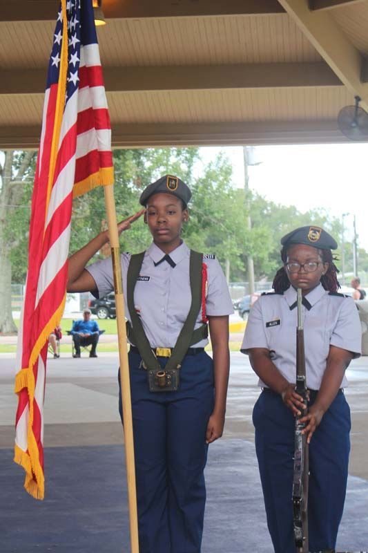 Two women in military uniforms holding an american flag